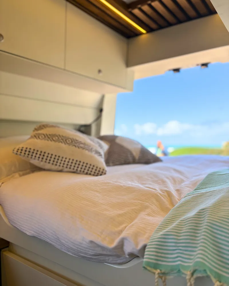 Lit double avec vue sur la plage depuis le van Renault Master, nuit paisible en bord de mer au Maroc.