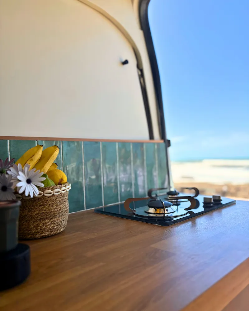 Cuisine équipée du van avec plaque gaz et panier de fruits, prête pour cuisiner face à la mer au Maroc.