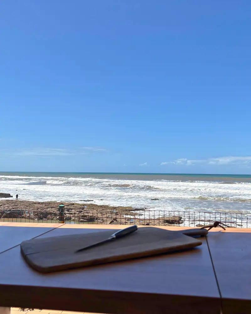 Vue sur l’océan Atlantique depuis la table du van aménagé, spot parfait pour petit-déjeuner au Maroc.